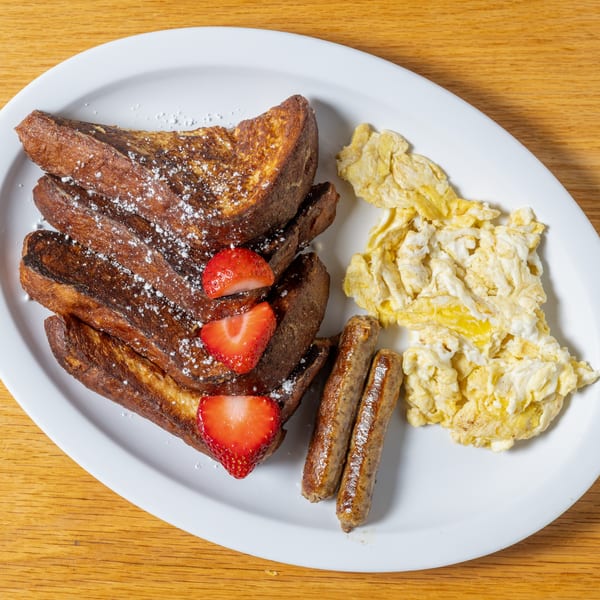 Cafe 26's French toast with powdered sugar, strawberries, sausage links, and scrambled eggs.