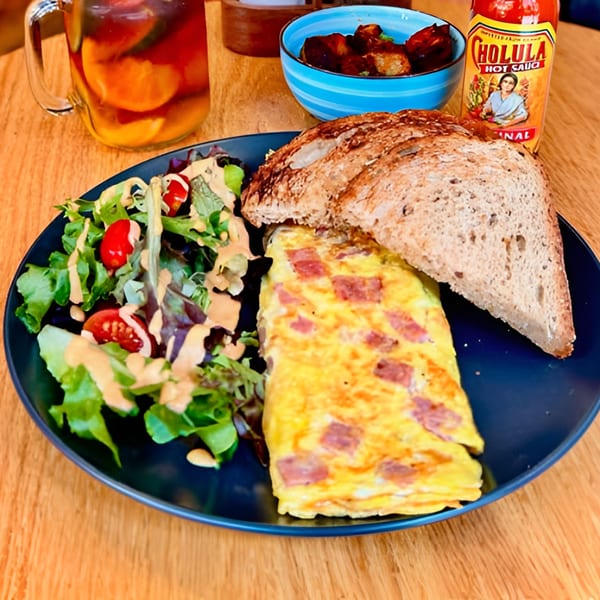 A Cafe 26 breakfast plate with a ham and cheese omelet, salad, toast, and iced tea.