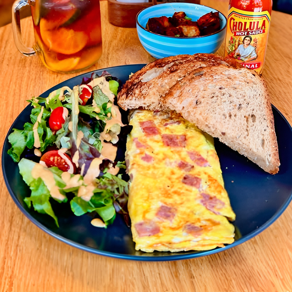 A Cafe 26 breakfast plate with a ham and cheese omelet, salad, toast, and iced tea.