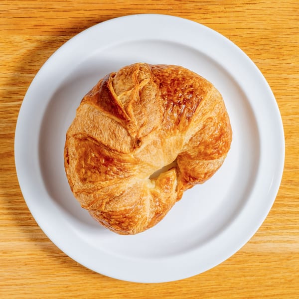 Golden-brown croissant on a white plate, viewed from above at Cafe 26.
