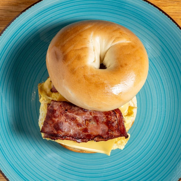 A Cafe 26 bagel sandwich with bacon, egg, and cheese on a blue plate.