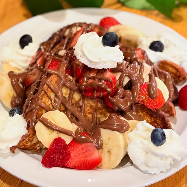 Cafe 26's French toast topped with chocolate drizzle, strawberries, bananas, whipped cream, and blueberries.